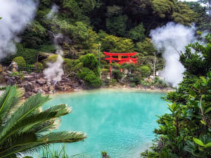 Beppu, Japan &ndash; hei&szlig;e Quelle mit dampfendem See und rotem Torii im dichten Gr&uuml;n
