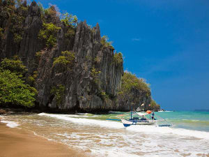 Puerto Princesa, Philippinen &ndash; Strand mit Kalkfelsen und Boot im seichten Wasser