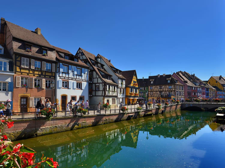 Reihe bunter Fachwerkh&auml;user mit steilen D&auml;chern unter klarem, blauem Himmel