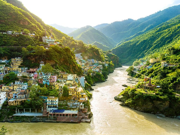 Bunte H&auml;user schmiegen sich an gr&uuml;ne Bergh&auml;nge entlang des Ganges im Sonnenlicht