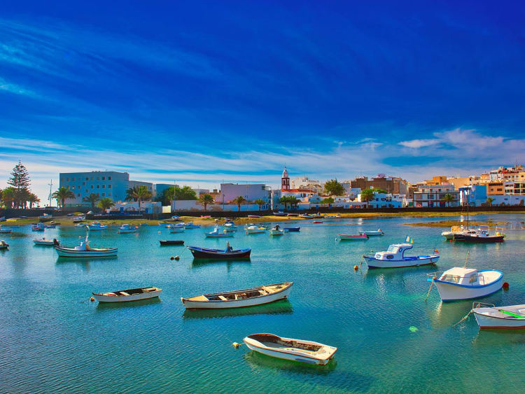 Arrecife, Spanien &ndash; Fischerboote schaukeln im t&uuml;rkisgr&uuml;nen Wasser vor der Altstadtkulisse