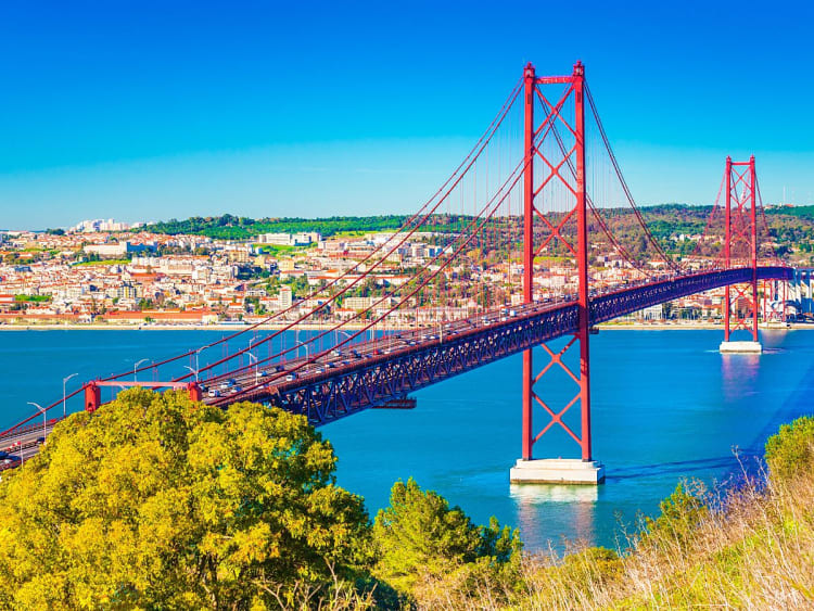 Lissabon, Portugal &ndash; Ponte 25 de Abril leuchtet &uuml;ber blauem Wasser