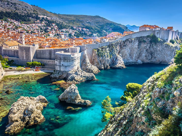 Dubrovnik, Kroatien &ndash; Stadtmauer umschlie&szlig;t Altstadt &uuml;ber t&uuml;rkisfarbenen Klippenbuchten
