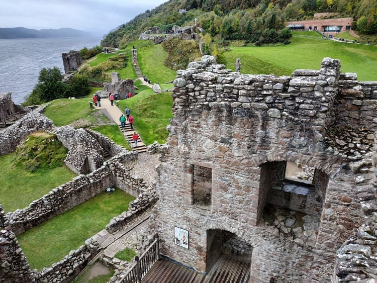 Invergordon, Schottland &ndash; Alte Burgreste und gr&uuml;ne H&uuml;gel &uuml;berblicken das dunkle Wasser