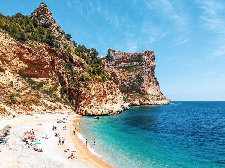 Alicante, Spanien &ndash; Badeg&auml;ste genie&szlig;en die Bucht unter steiler Felsklippe