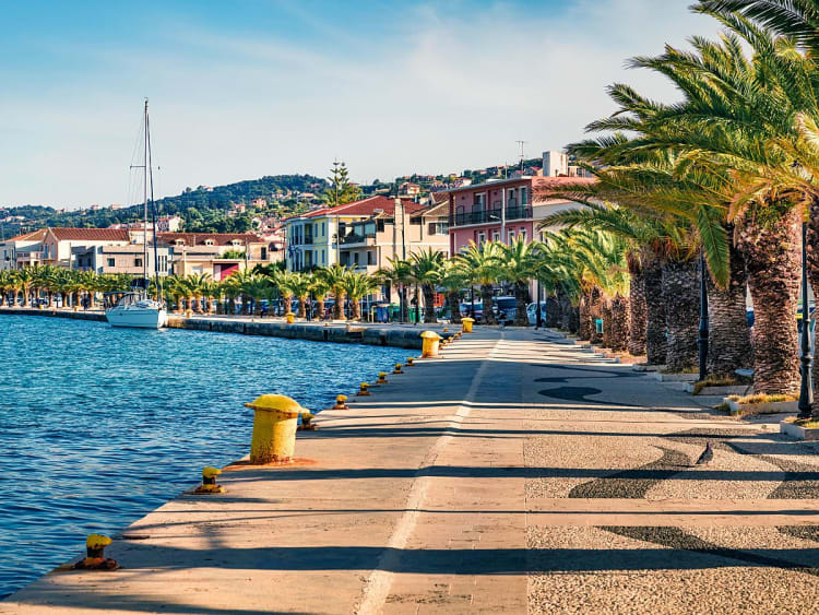 Argostoli, Griechenland &ndash; mediterrane Hafenpromenade mit Blick auf Berge und Segelboot