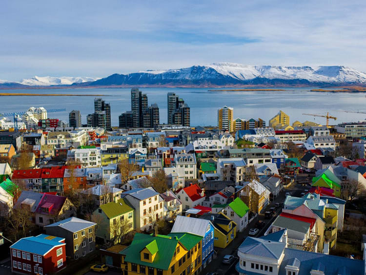 Reykjav&iacute;k, Island &ndash; bunte D&auml;cher vor glitzernder Bucht und Schneegipfeln