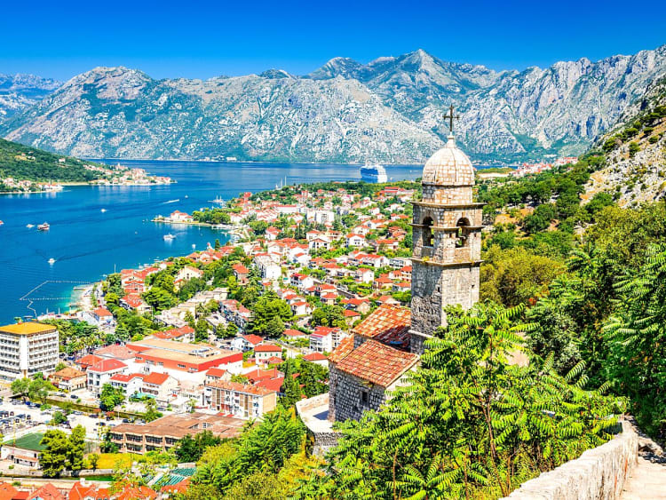Kotor, Montenegro &ndash; Kirchturm &uuml;ber Altstadtd&auml;chern mit Blick auf die Bucht