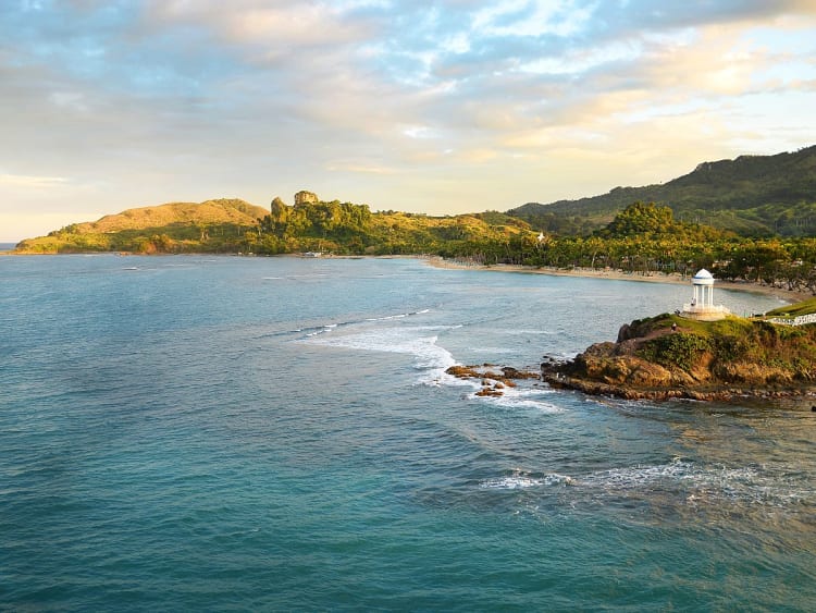 Amber Cove, Dominikanische Republik &ndash; Wei&szlig;er Turm auf felsiger Kapspitze &uuml;ber ruhigem Strand und gr&uuml;nem Hang