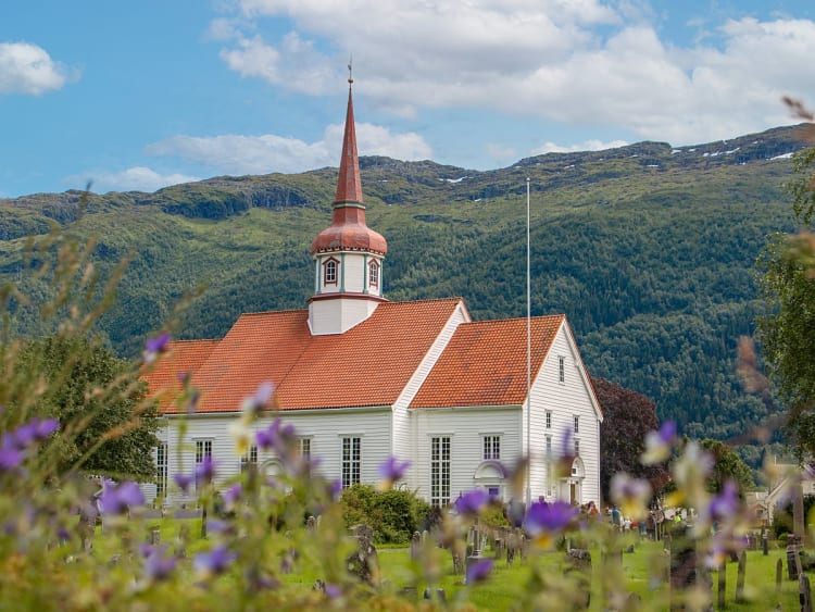 Nordfjordeid, Norwegen &ndash; Wei&szlig;e Holzkirche mit rotem Turmdach vor gr&uuml;ner Bergkulisse