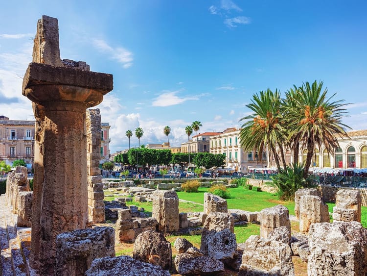 Syrakus, Italien &ndash; Ruinen des Apollo-Tempels zwischen Palmen und barocken Fassaden