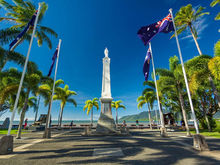Cairns, Australien &ndash; Wei&szlig;es Kriegsdenkmal von Palmen und Flaggen umrahmt am Meer