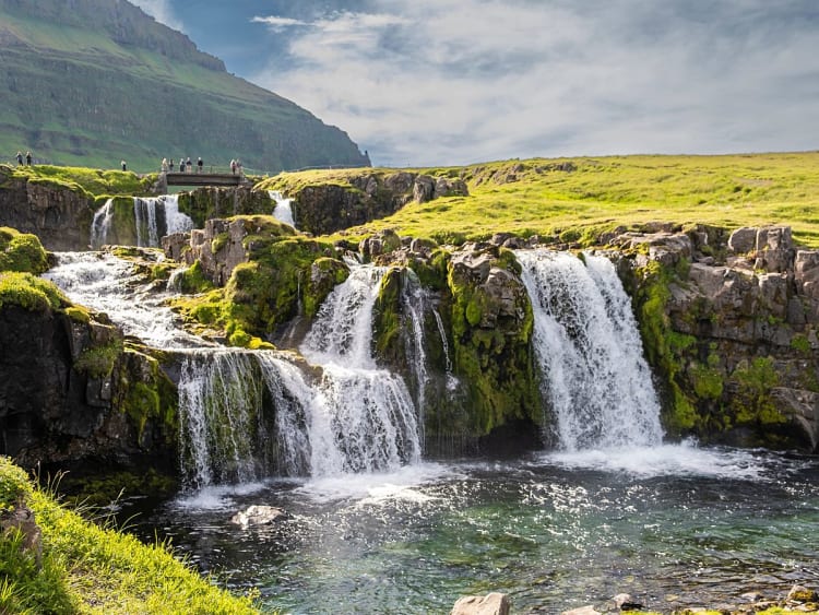 Grundarfj&ouml;r&eth;ur, Island &ndash; Breit gef&auml;cherte Wasserf&auml;lle st&uuml;rzen &uuml;ber moosige Felsen ins Tal