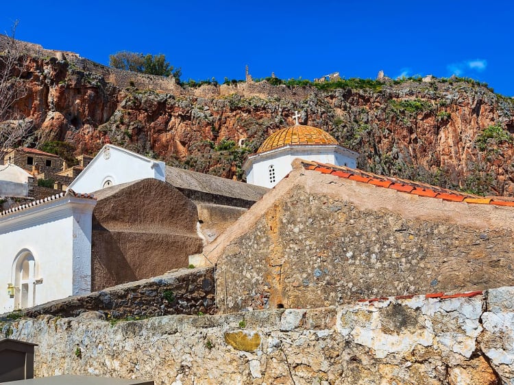 Monemvasia, Griechenland &ndash; Wei&szlig;-braune Kirche schmiegt sich unter roten Klippen