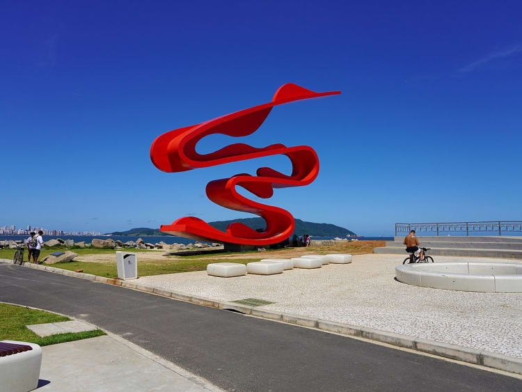 Santos, Brasilien &ndash; Rote K&uuml;stenskulptur &bdquo;Onda&ldquo; hebt sich vor tiefblauem Himmel ab