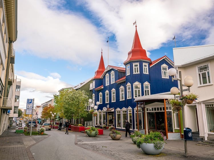 Akureyri, Island - Stra&szlig;enszene mit blauem Holzhaus und roten T&uuml;rmen