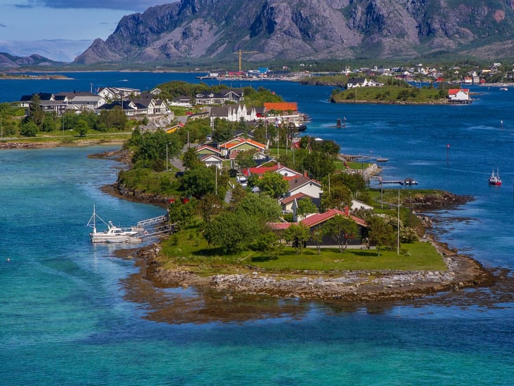 Br&oslash;nn&oslash;ysund, Norwegen - Inselort mit bunten H&auml;usern vor felsigen Bergen