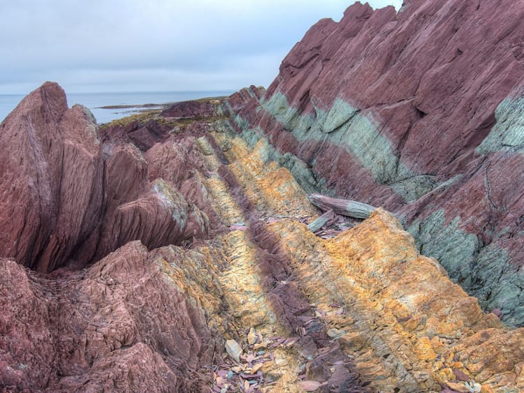 B&aring;tsfjord, Norwegen - Schichtgestein in Rot, Gr&uuml;n und Ocker am Meer