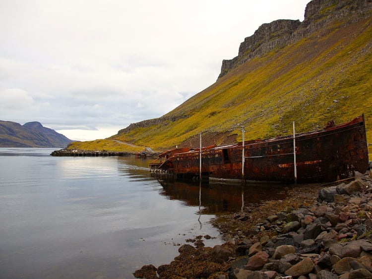 Dj&uacute;pav&iacute;k, Island - Rostiges Schiffswrack am Ufer zwischen Bergen