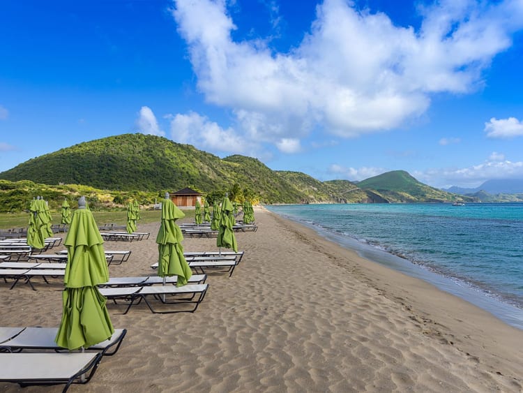 Carambola Beach, St. Kitts und Nevis - Strandliegen mit gr&uuml;nen Schirmen am Meer