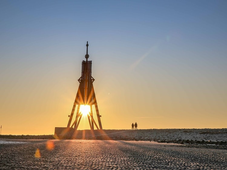 Cuxhaven, Deutschland - Sonnenstrahlen durch Kugelbake am Wattenmeer
