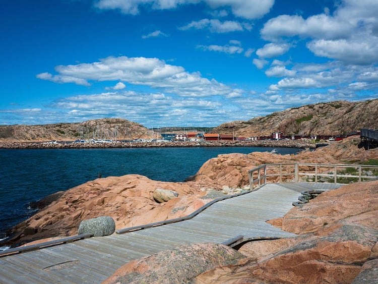 Lysekil, Schweden &ndash; Holzweg f&uuml;hrt &uuml;ber rote Felsen zum Hafen am Meer