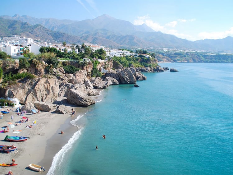 M&aacute;laga, Spanien &ndash; K&uuml;ste mit Badeg&auml;sten am Strand unter felsigen Klippen