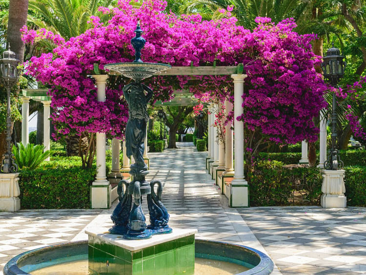 C&aacute;diz, Spanien &ndash; bl&uuml;hende Bougainvillea im Park mit kunstvollem Brunnen