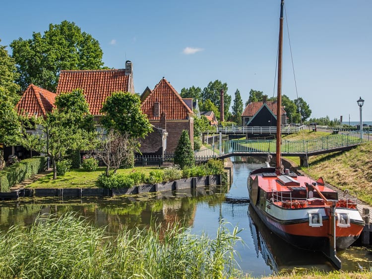 Enkhuizen, Niederlande &ndash; rotes Segelboot im Hafen vor Backsteinh&auml;usern