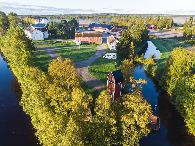 Kemi, Finnalnd - rote Holzh&auml;user am Flussufer zwischen gr&uuml;nen B&auml;umen