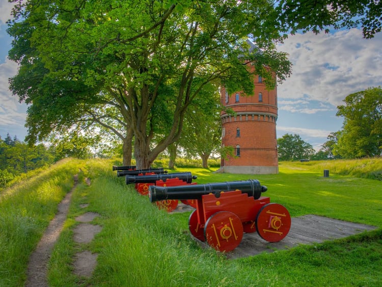 Nyborg D&auml;nemark &ndash; rote Kanonen am Wall vor historischem Backsteinturm