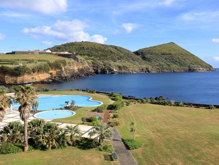 Isla Terceira, Azoren &ndash; Poolanlage mit Palmen und Blick auf Bucht und H&uuml;gel