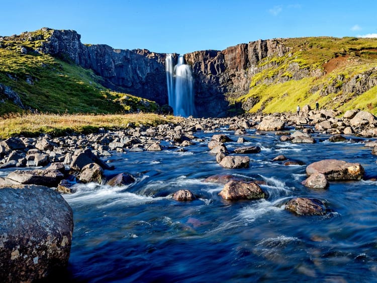 Sey&eth;isfj&ouml;r&eth;ur, Island &ndash; Majest&auml;tischer Wasserfall st&uuml;rzt zwischen gr&uuml;nen Felsen herab