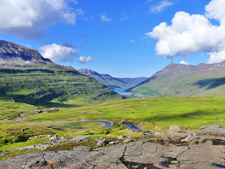 Sey&eth;isfj&ouml;r&eth;ur, Island &ndash; Panoramablick ins gr&uuml;ne Tal mit kurviger Stra&szlig;e und Fjord