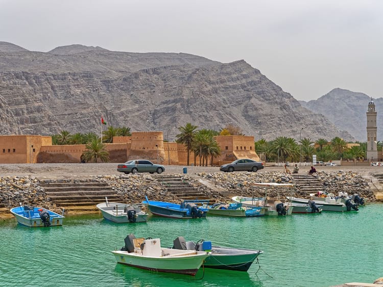 Khasab, Oman &ndash; Hafen mit kleinen Booten und historischer Festung vor karger Berglandschaft