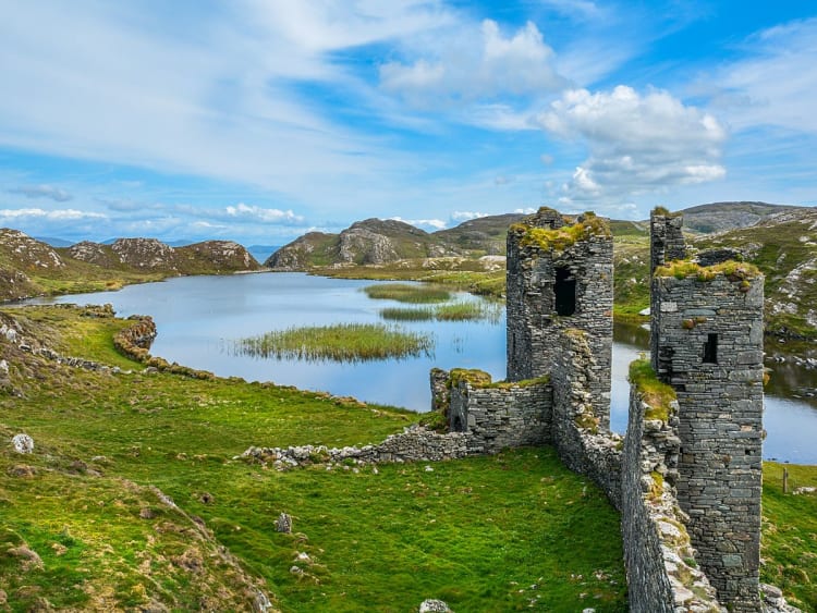 Cork, Irland &ndash; Alte Burgruine inmitten einer h&uuml;geligen Seenlandschaft unter blauem Himmel