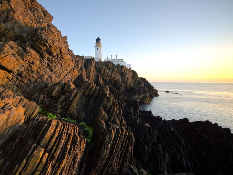 Douglas, Isle of Man &ndash; Leuchtturm auf schroffen Klippen im goldenen Licht des Sonnenuntergangs