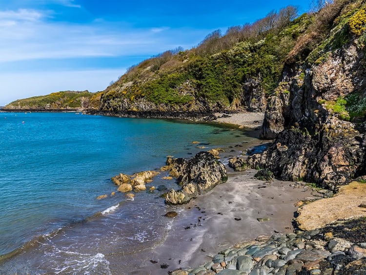 Fishguard, Wales &ndash; Malerische Bucht mit t&uuml;rkisfarbenem Meer, Felsen und &uuml;ppiger Vegetation