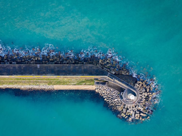 Fishguard, Wales &ndash; Drohnenaufnahme des Hafens mit Leuchtturm und Wellenbrechern im t&uuml;rkisblauen Wasser