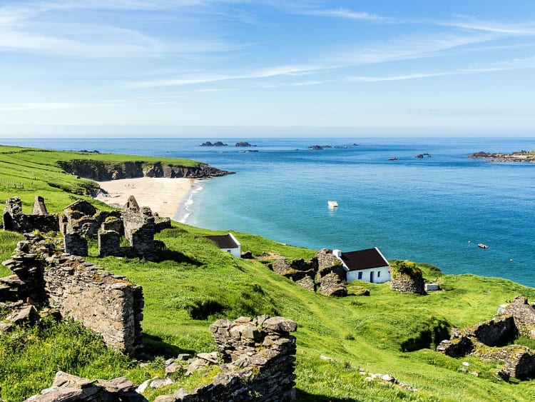 Dingle, Irland &ndash; Alte Steinh&auml;user und Ruinen mit Blick auf den Strand und das blaue Meer