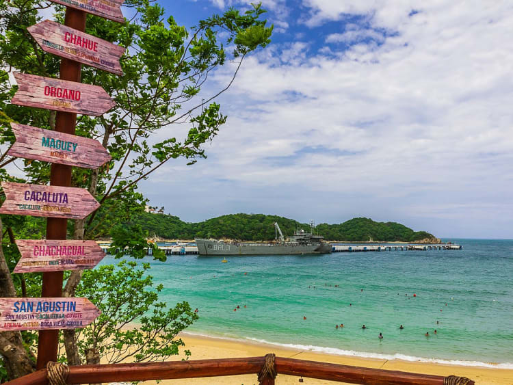 Huatulco, Mexiko &ndash; t&uuml;rkisfarbenes Meer und Schiff am Pier hinter tropischem Strand