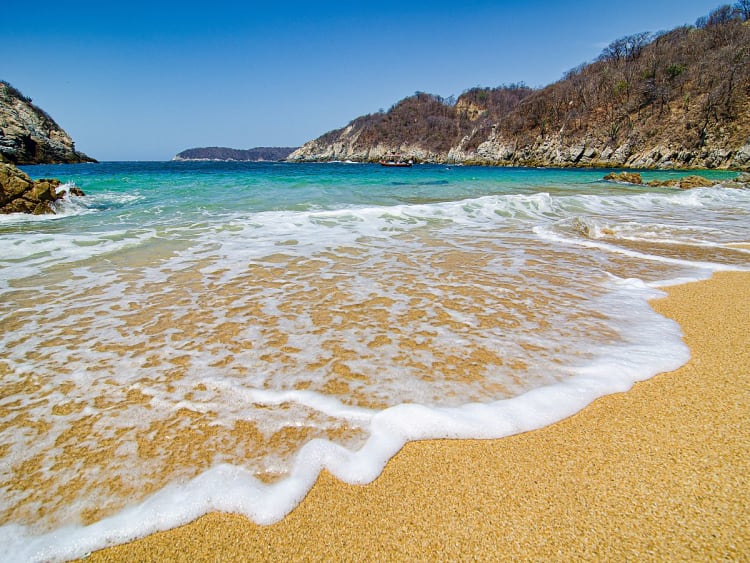 Huatulco, Mexiko &ndash; sanfte Wellen laufen &uuml;ber goldenen Naturstrand zwischen Felsen