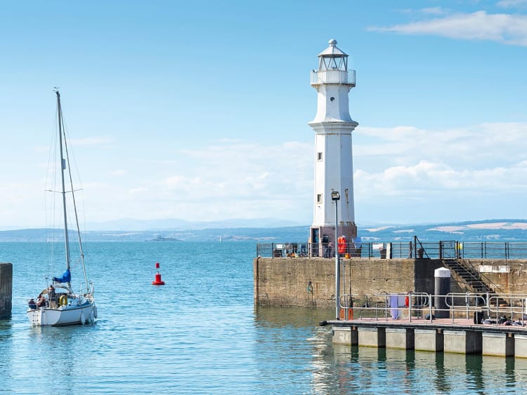 Newhaven, Schottland &ndash; wei&szlig;er Leuchtturm am Pier mit Segelboot vor weitem Meer