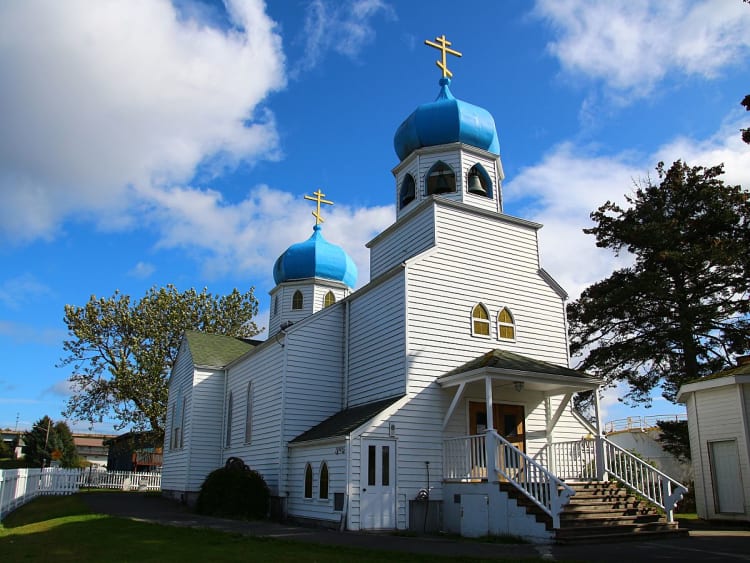 Kodiak, USA &ndash; Wei&szlig;e Holzkirche mit blauen Kuppeln leuchtet unter weiten Wolken
