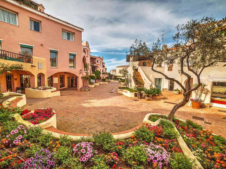 Porto Cervo, Italien &ndash; Farbenfroher Innenhof mit bl&uuml;henden Beeten und Olivenb&auml;umen