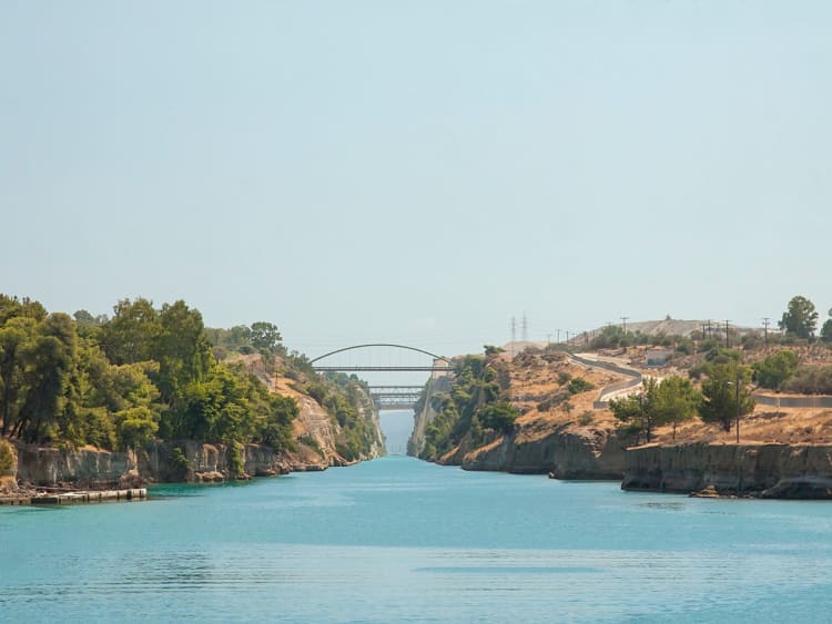 Korinthkanal, Griechenland &ndash; Ruhiger Kanal mit Br&uuml;cken im Hintergrund und gr&uuml;nen Ufern