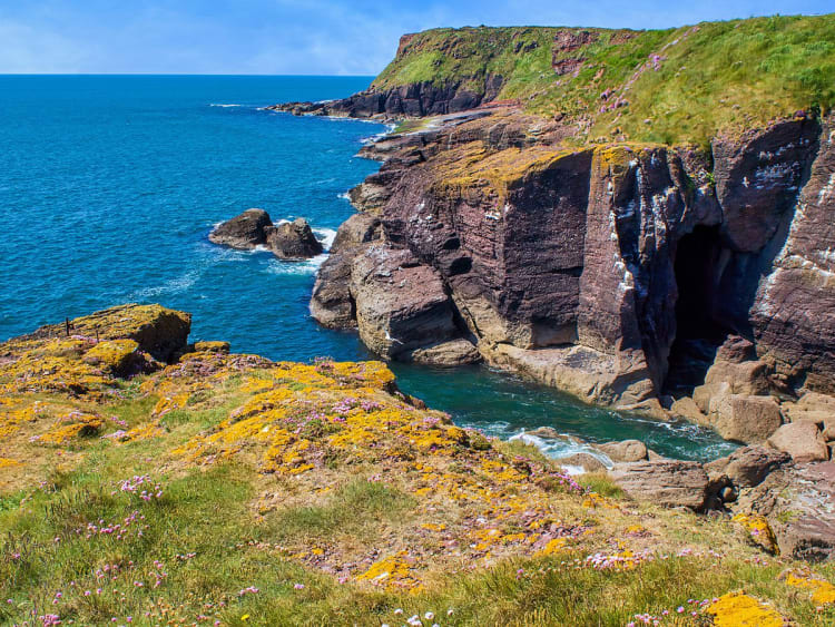 Dunmore East, Irland &ndash; K&uuml;stenfelsen mit Meeresgrotte und gr&uuml;nen Wiesen
