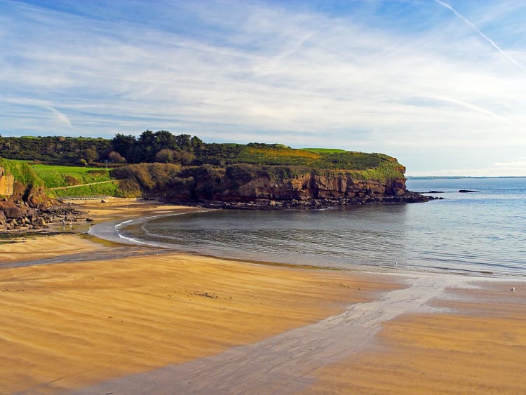 Dunmore East, Irland &ndash; Goldener Sand vor Felsen am Meer