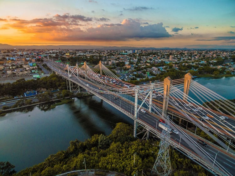 Santo Domingo, Dominikanische Republik - Schr&auml;gseilbr&uuml;cke &uuml;ber Fluss mit Blick auf die Stadt