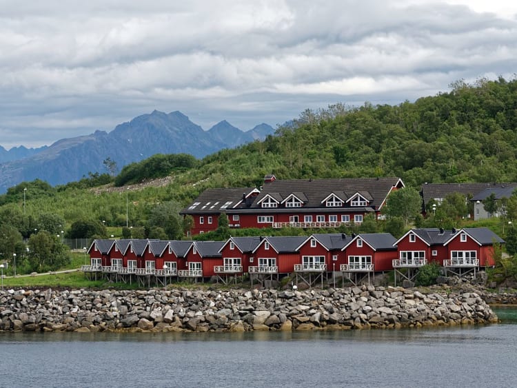 Stokmarknes, Norwegen - K&uuml;stensiedlung mit roten H&auml;usern und Berglandschaft